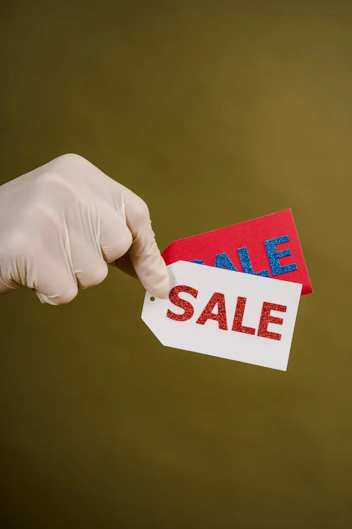 why-choose-us Gloved hand holding red and white sale tags on a green background, emphasizing shopping and discounts.